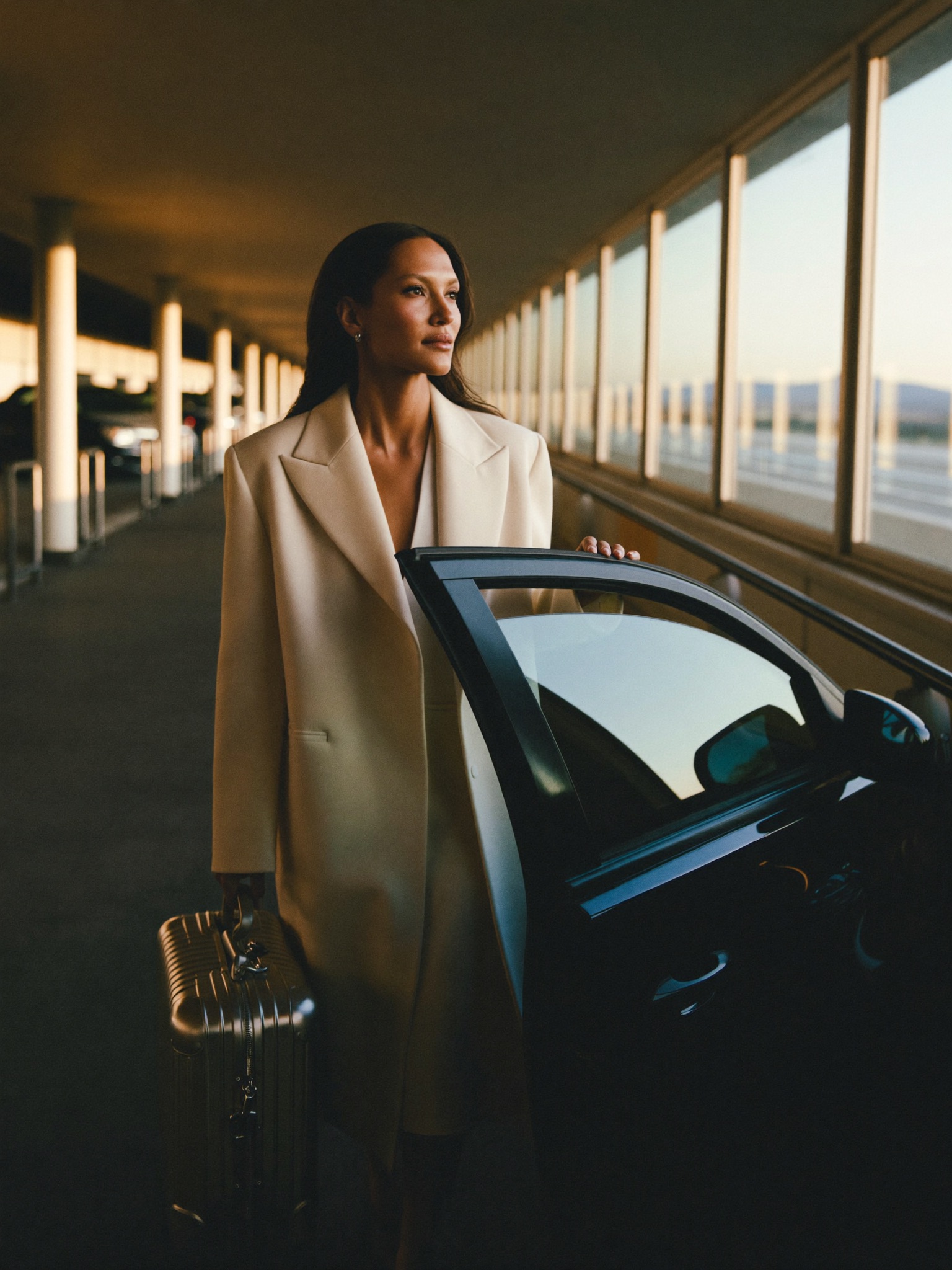 A composed woman departing for her journey, luggage in hand, at ease in the golden light